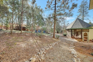 A residential property with a gravel driveway, a covered outdoor seating area, and a variety of trees. - Pine Grove Retreat for 10 | Game Room + Fire Pit (Pine Grove)