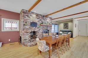 A dining area with a brick fireplace, wooden dining table, and chairs. - Pine Grove Retreat for 10 | Game Room + Fire Pit (Pine Grove)