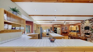 A spacious kitchen with wooden cabinets, a central island, and a brick wall. - Pine Grove Retreat for 10 | Game Room + Fire Pit (Pine Grove)