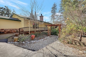A residential building with a covered porch, a brick chimney, and a garden with gravel and plants.