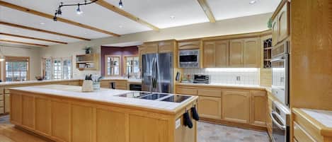 A spacious kitchen with wooden cabinetry, a large island, and modern appliances.