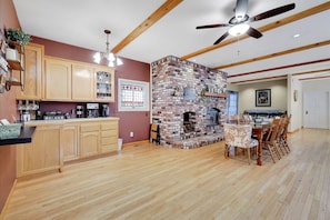 A spacious kitchen with wooden cabinets, a brick fireplace, and a dining area with a table and chairs.