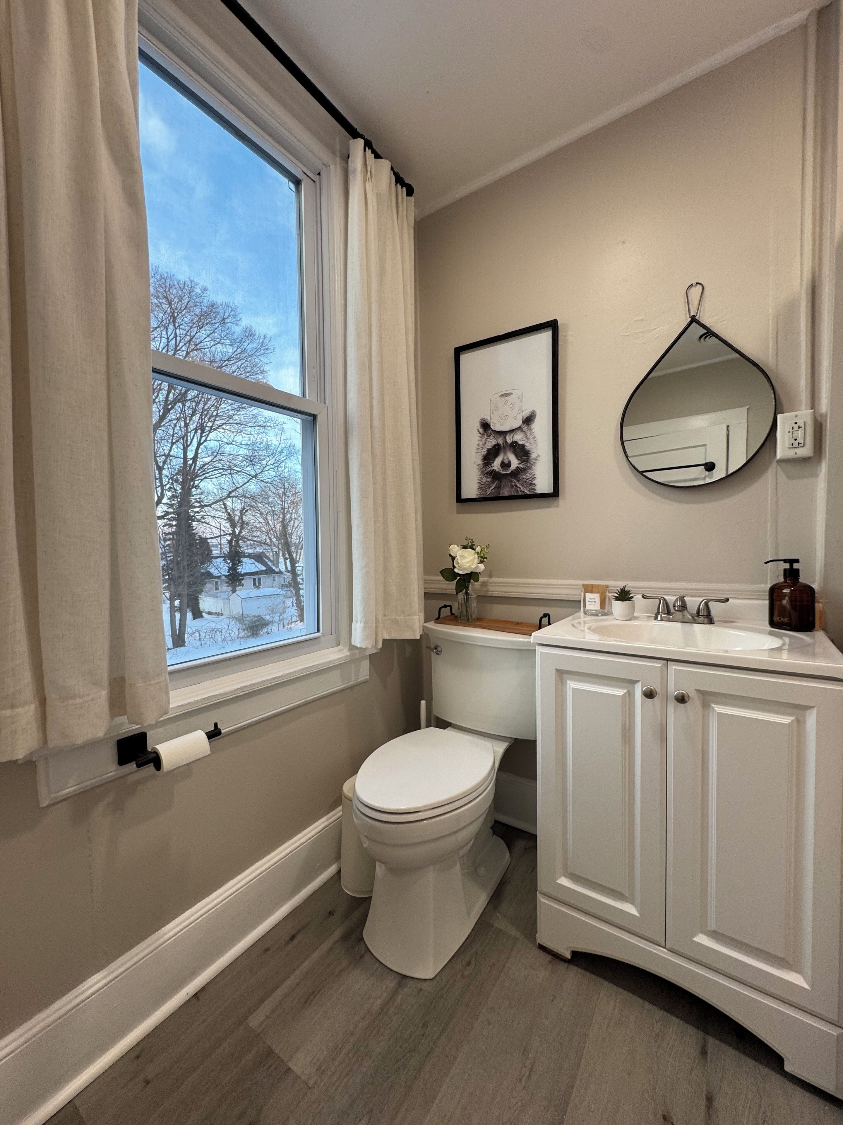 A bathroom with a toilet, sink, and window.