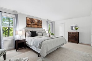 Una camera da letto con un letto, comodini, una cassettiera, uno specchio e un quadro appeso al muro.