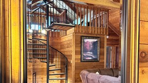 A wooden interior with a spiral staircase, a framed picture on the wall, and a sofa. - New listing! Cabin Mountain Escape Near Atlanta -  Friends • Family • Romantic (Jasper)