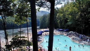 A swimming pool surrounded by trees, with a view of a lake and mountains in the background. - New listing! Cabin Mountain Escape Near Atlanta -  Friends • Family • Romantic (Jasper)