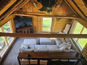 A cozy log cabin interior with a sofa, wooden table, and a television. - 5-bedroom cabin - Where peaceful vacationing meets nearby adventures  (Wisconsin Dells)