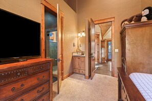 A bedroom with a wooden dresser, a bed, and a television. - Deschutes Reserve- Riverfront Home with Hot Tub (Sunriver)