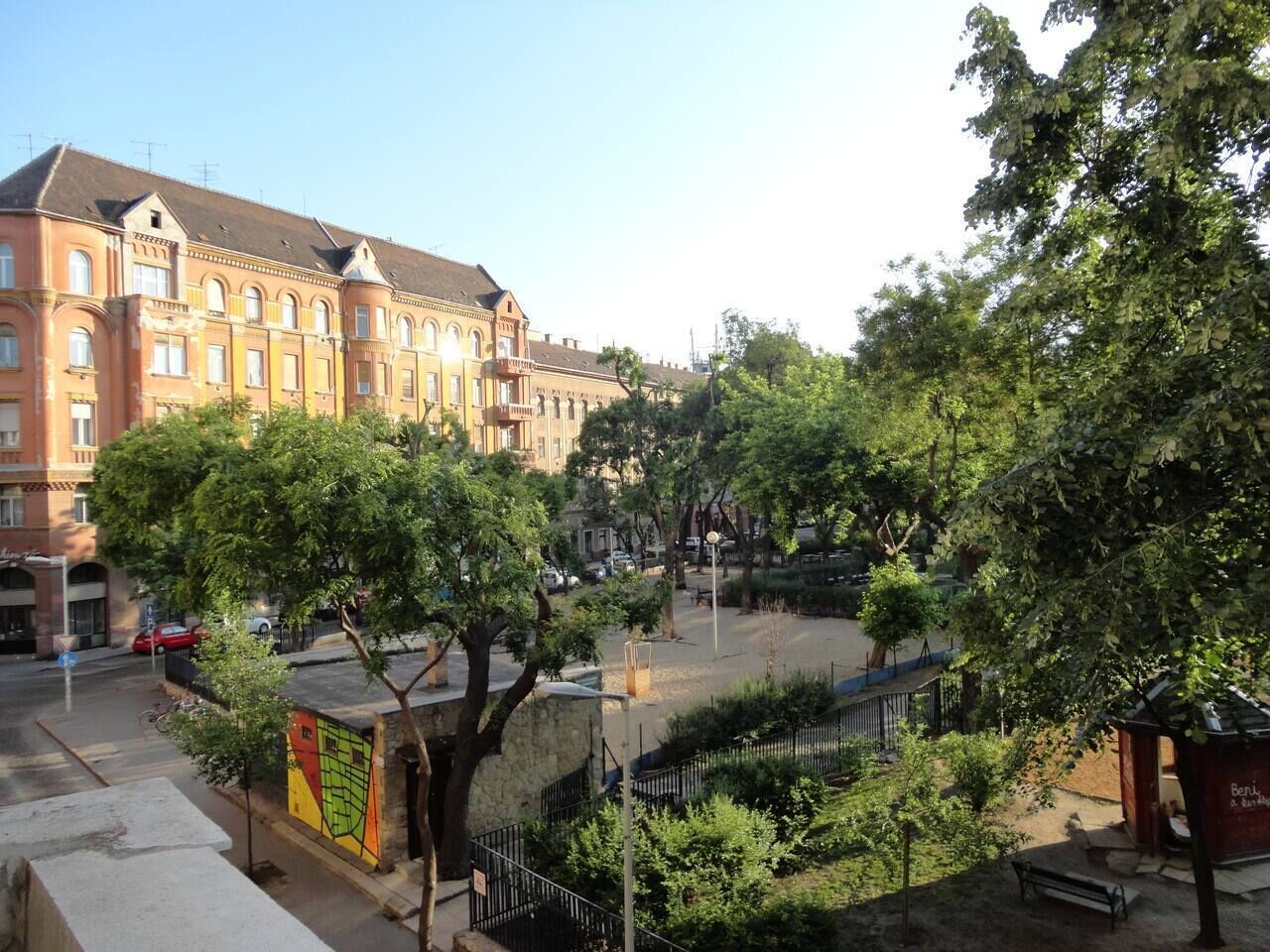 A courtyard with trees, benches, and a building with multiple windows.