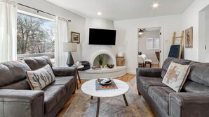Ein modernes Wohnzimmer mit Ledersofas, einem weißen Kamin und einem Flachbildfernseher.