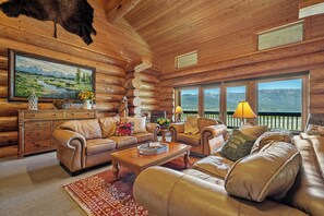 Ein Holzblockhaus-Interieur mit einer Couch, einem Couchtisch und einem Landschaftsbild.