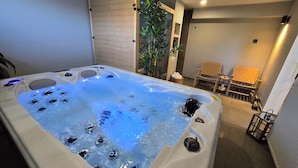 A hot tub with bubbles, a wooden chair, a potted plant, and a small table with a candle. - Hilltop house with jacuzzi, sauna, pool, barbecue, and orchard (Voloder)