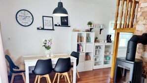A modern living room with a dining area, a black wood-burning stove, bookshelves, and decorative items. - Hilltop house with jacuzzi, sauna, pool, barbecue, and orchard (Voloder)
