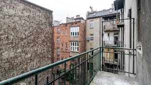 A narrow alleyway with a green metal railing, brick buildings, and a building with a satellite dish. - Słowackiego Serene Studio with Balcony (Katowice)
