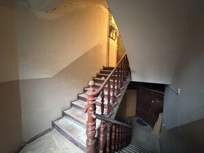 Eine Treppe mit Holzspindeln und Geländer, die zu einem Podest mit einer Tür führt.