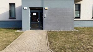 En bygningseingang med en glasdør, et lille vindue og et skilt med nummer 54.