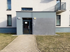 A building entrance with a glass door, a small window, and a number '54' sign. - Jesionowa Spacious Apartment (Wrocław)