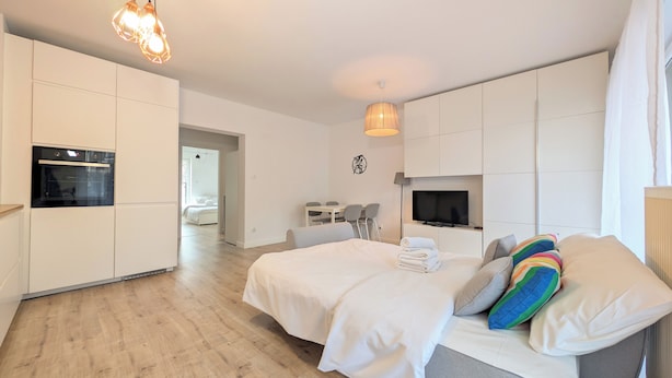 Et moderne hotelværelse med en stor seng, et fjernsyn, et spiseområde og et tekøkken.