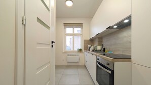Una cocina moderna con armarios blancos, horno empotrado y ventana con vista a la ciudad.