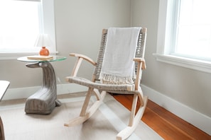 A rocking chair with a white towel, a glass table with a vase, and a lamp. - Soothing 2-bedroom cottage with Sauna in Old Orchard Beach (Old Orchard Beach)