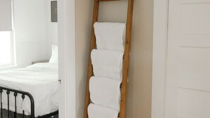A room with a wooden ladder leaning against a wall, a bed with white bedding, and a woven rug on the floor. - Soothing 2-bedroom cottage with Sauna in Old Orchard Beach (Old Orchard Beach)