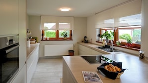 Une cuisine moderne dotée d’un îlot central, d’un four encastré et d’une fenêtre donnant sur un paysage verdoyant.