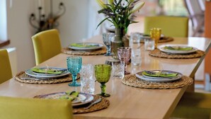 Une table à manger dressée avec des assiettes, des verres et un vase de fleurs.