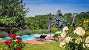Un espace aménagé au bord de la piscine, avec des chaises longues, des parasols et une terrasse en bois.