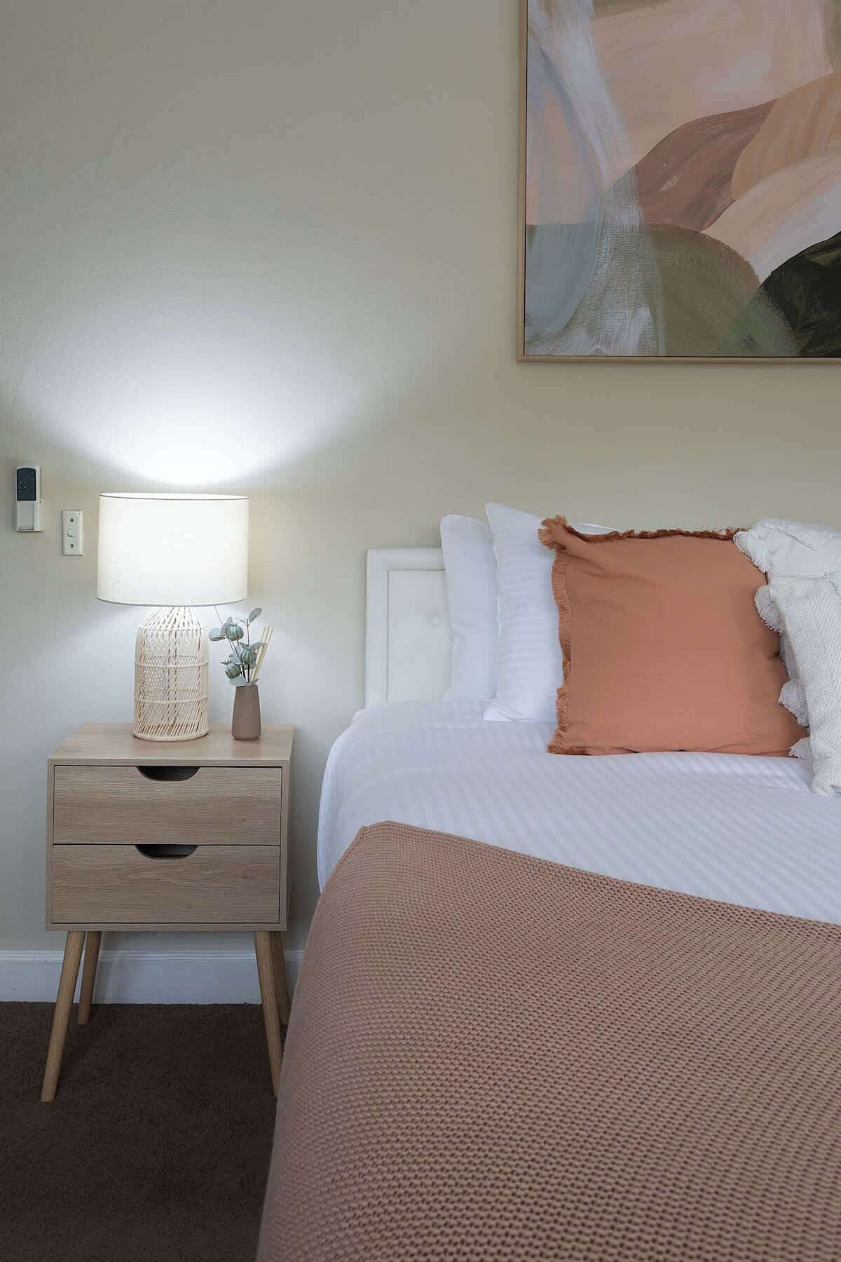 Camera d'albergo ordinata con un letto, un comodino con una lampada e un purificatore d'aria a parete.