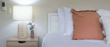 Camera d'albergo ordinata con un letto, un comodino con una lampada e un purificatore d'aria a parete.