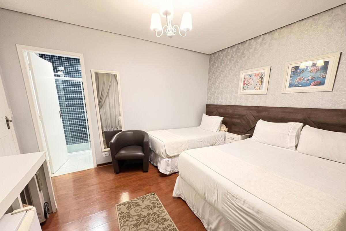 A hotel room with two beds, a desk, a chair, and a small rug.