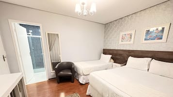 Una habitación de hotel con dos camas, un escritorio, una silla y una alfombra pequeña.