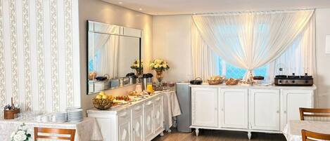 A dining area with a buffet setup, a large mirror, and a chandelier.