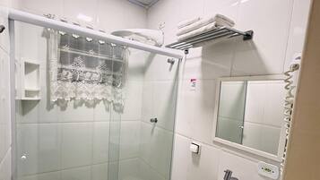 A bathroom with a glass-enclosed shower, a toilet, a sink, and a towel rack.