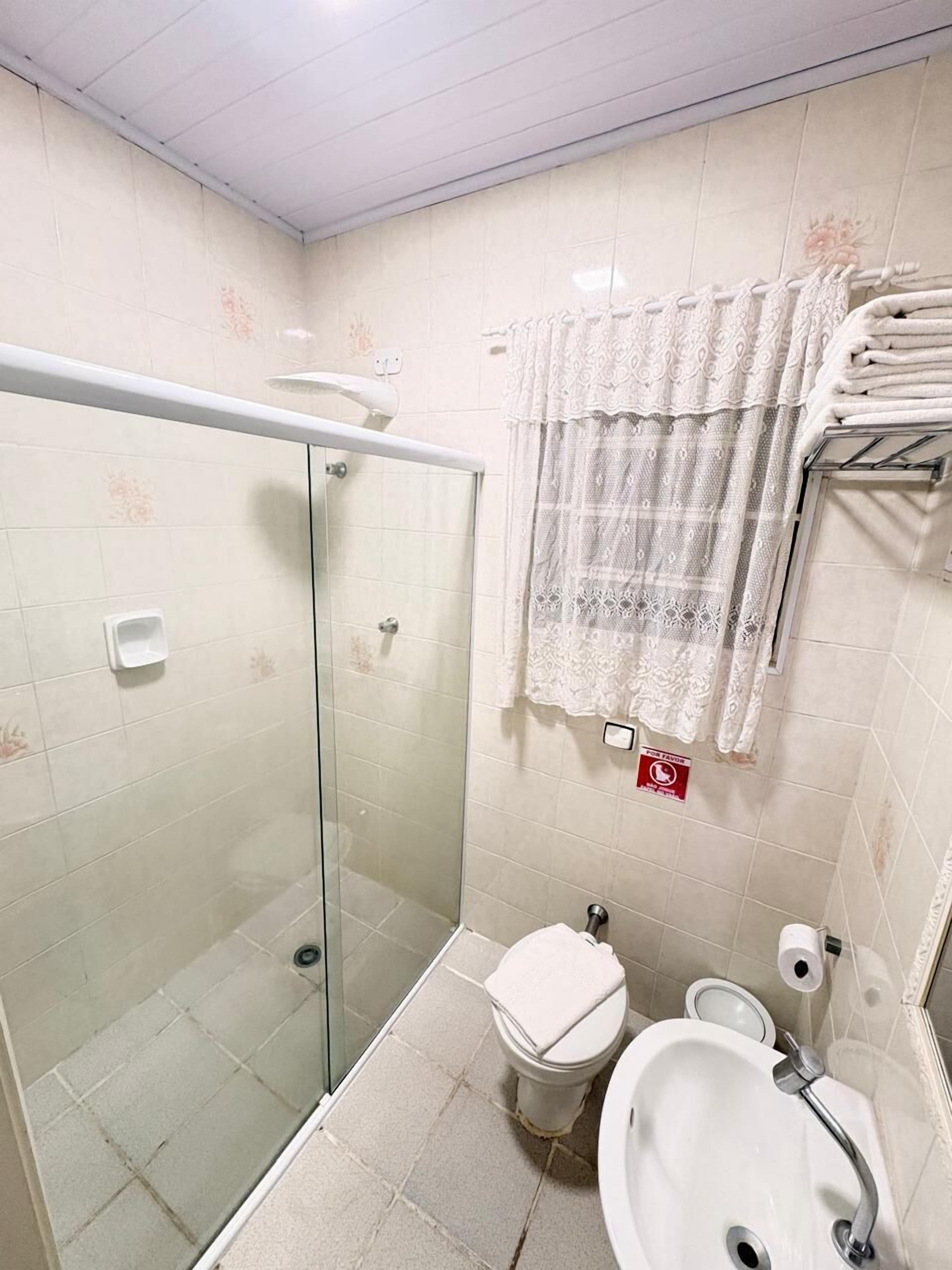 A bathroom with a glass-enclosed shower, a toilet, and a sink.