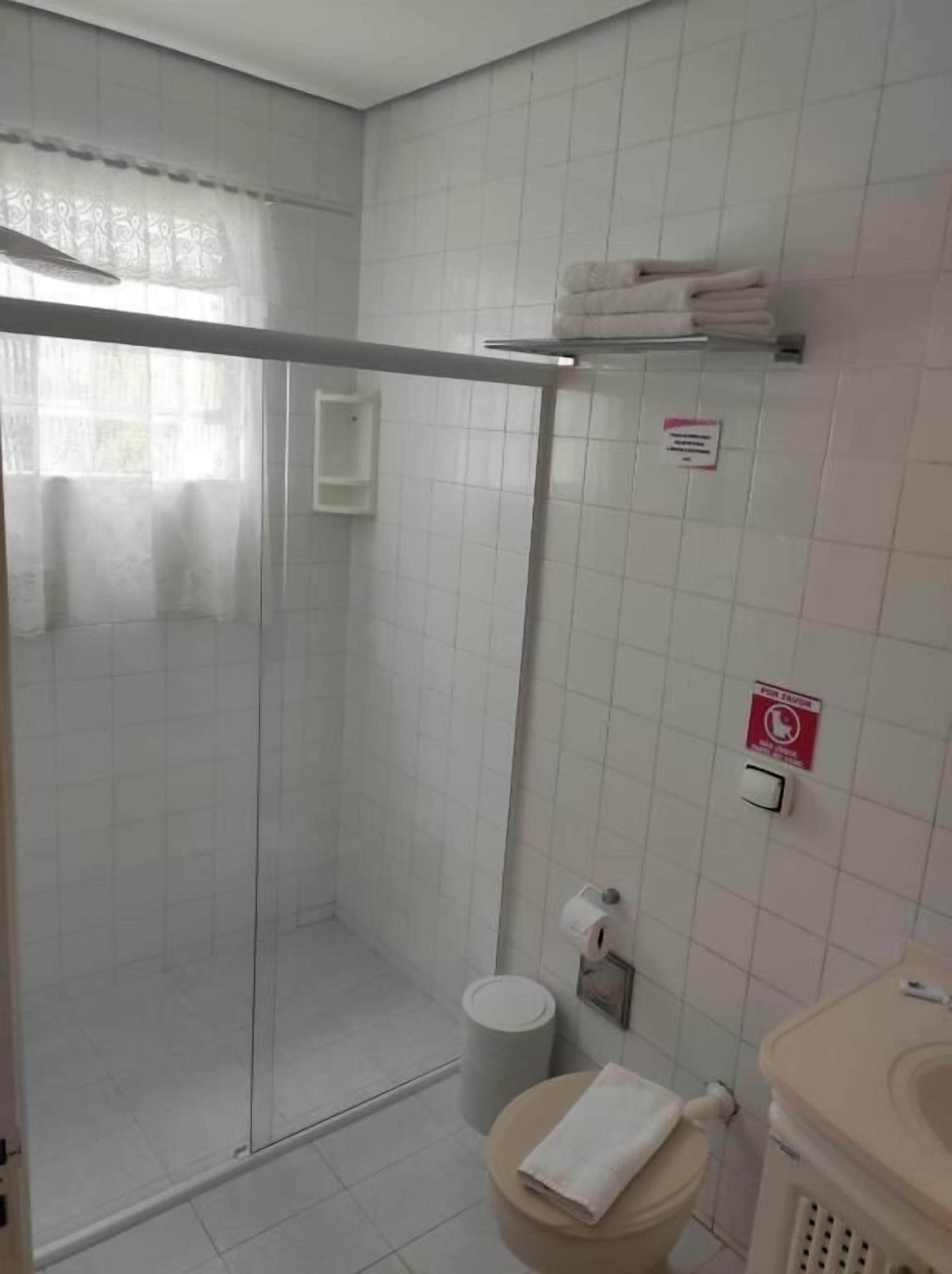 A bathroom with a glass shower enclosure, a toilet, a sink, and a towel rack.