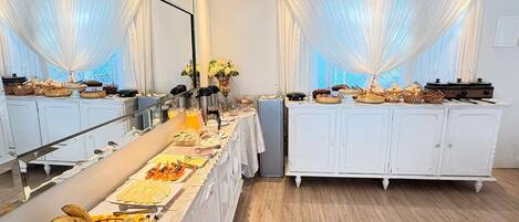 Una mesa de buffet con diversos alimentos y una cesta de frutas.