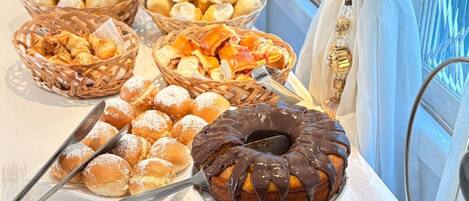 A buffet table with various baked goods, including bread, pastries, and a chocolate bundt cake.