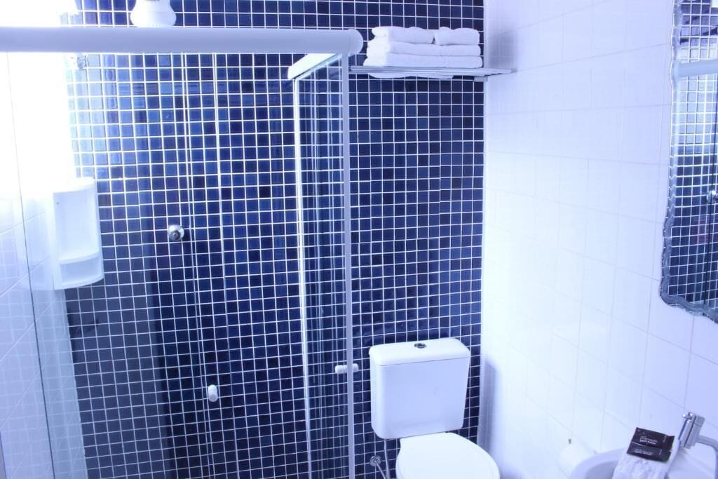 Kylpyhuoneessa on sinisillä laatoilla päällystetty seinä, valkoinen WC-istuin ja pyyheteline, jossa on siististi taiteltuja pyyhkeitä.