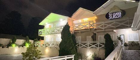 A two-story building with a balcony and a sign that reads "POUSADA SUISE".