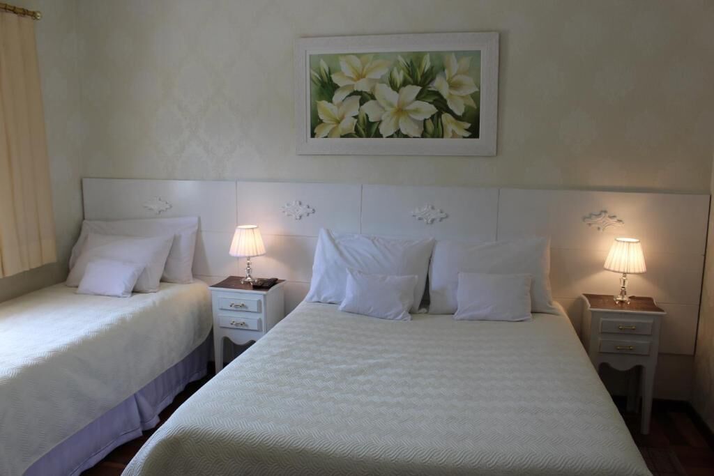 Une chambre d’hôtel avec deux lits, chacun étant équipé de draps blancs et de deux tables de chevet assorties.
