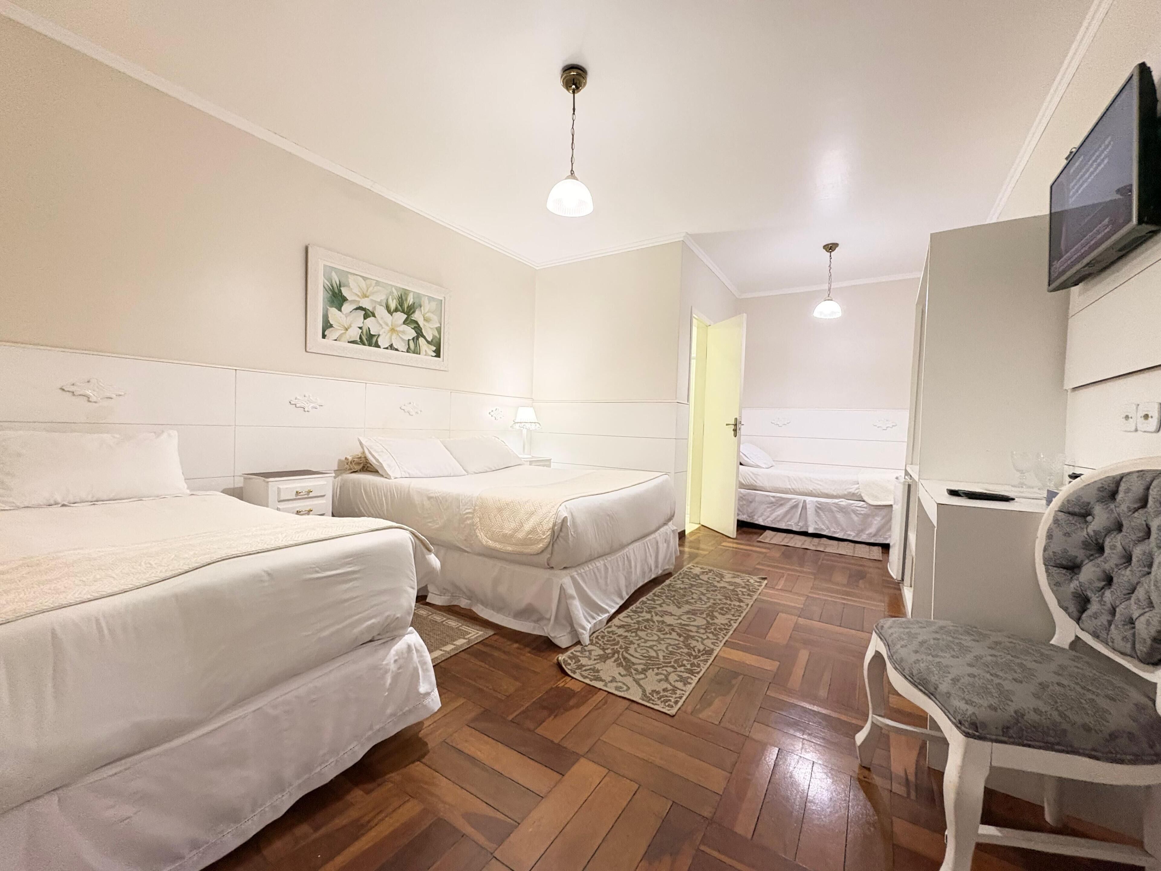 Habitación de hotel con dos camas, un escritorio, una silla, un televisor y un cuadro en la pared.