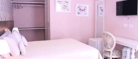 A pink-themed bedroom with a bed, a desk, a chair, and a television.