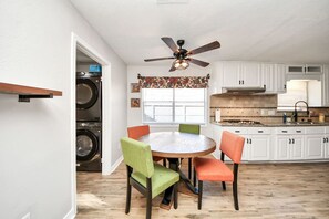 A compact kitchen with a dining area, a ceiling fan, and a built-in washer and dryer. - Creekhaven Getaway w/ Basketball Court | Sleeps 16 (Houston)