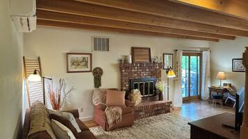Una sala de estar acogedora con chimenea, un sofá, una mesita de centro y un televisor.
