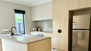 A modern kitchen with a central island, stainless steel appliances, and light wood cabinetry.