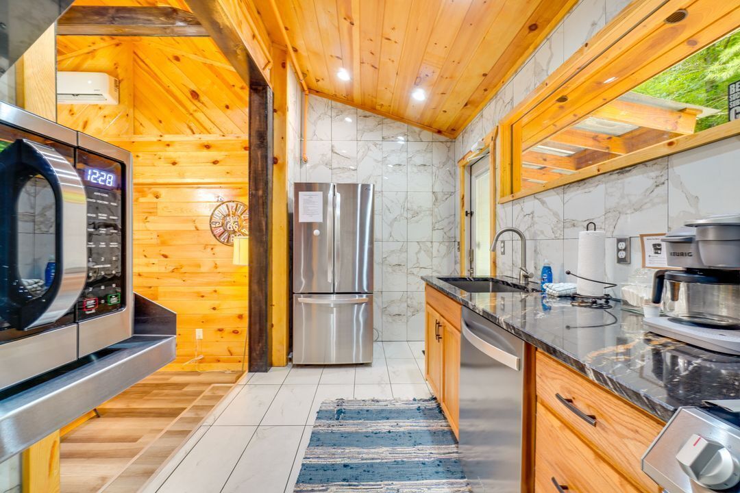 A modern kitchen with wooden walls, stainless steel appliances, and a marble backsplash.