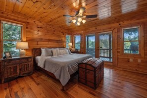 A wooden cabin bedroom with a bed, nightstands, a lamp, and a chest of drawers. - Johnny's Lakeside Hideaway - Private Dock | Hot Tub | Game Room (Morganton)