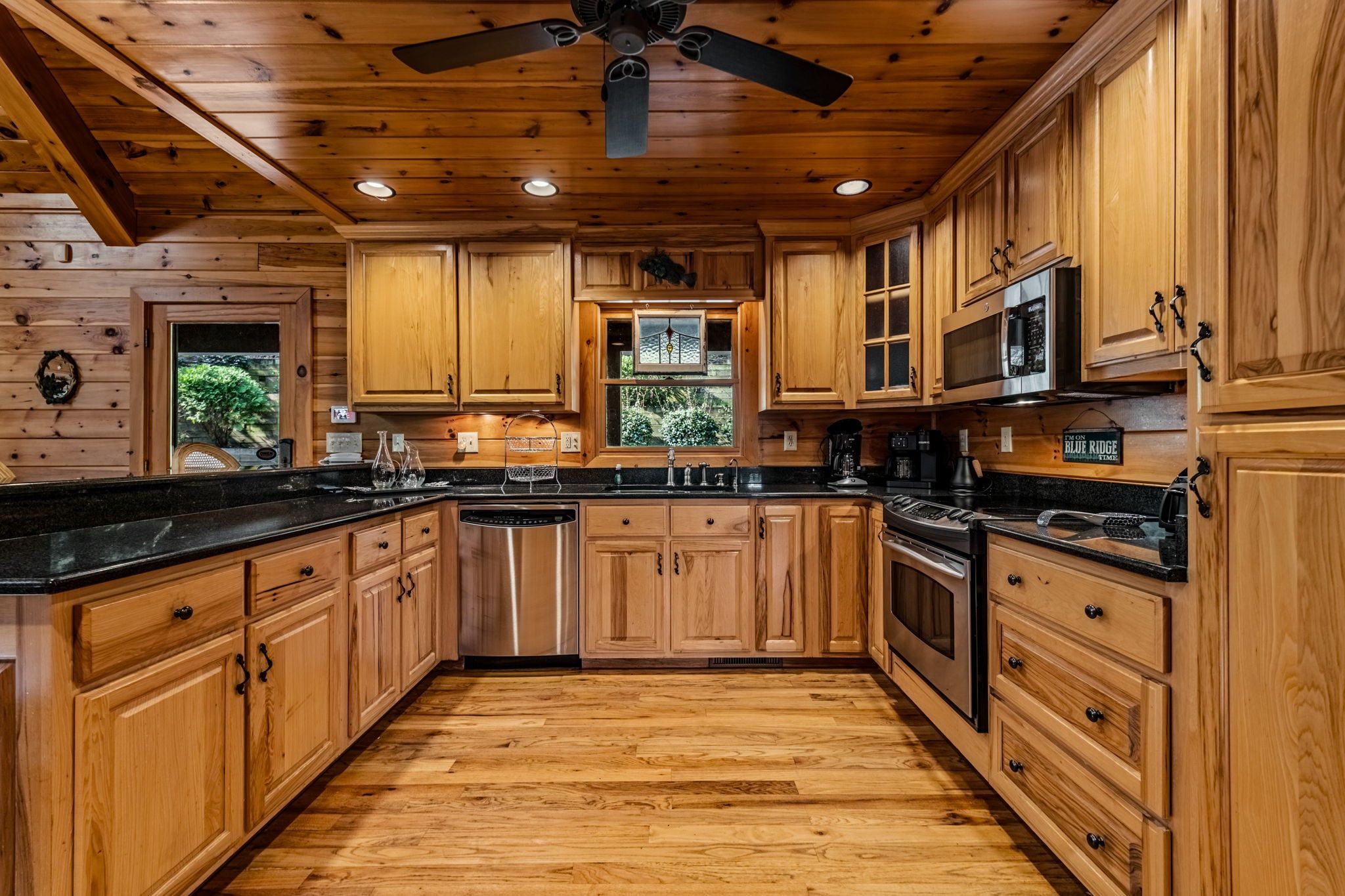 Une cuisine avec des meubles en bois, un réfrigérateur en acier inoxydable et un ventilateur de plafond.