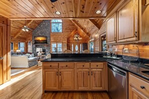 A spacious kitchen with wooden cabinets, a stone fireplace, and a large island. - Johnny's Lakeside Hideaway - Private Dock | Hot Tub | Game Room (Morganton)